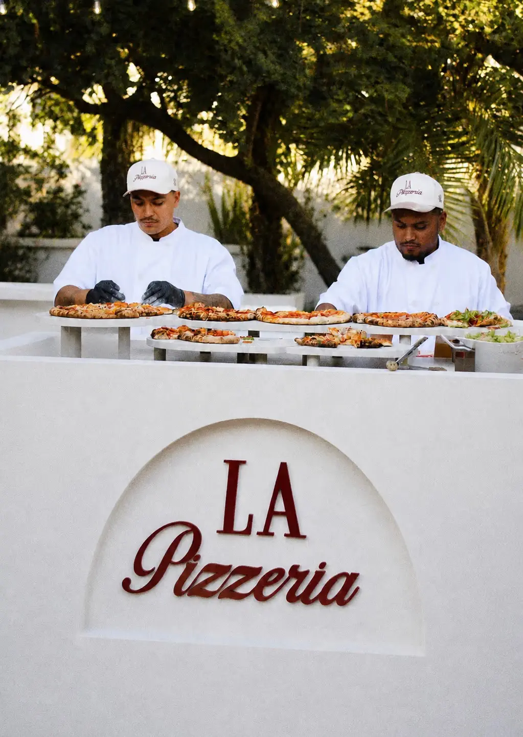 La Pizzeria chefs serving fresh wood-fired pizza at a private event